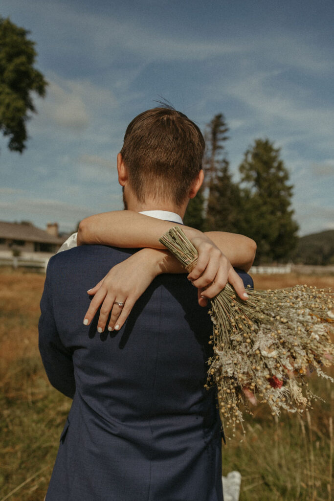 Groom wraps his arms around bride’s waist and pulls her in for a kiss in a golden pasture during their Washington elopement