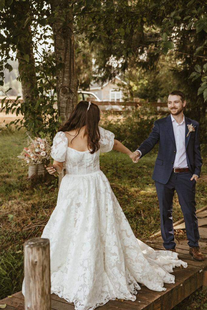 Bride and groom stroll across a footbridge at a historic bed and breakfast near Olympic National Park